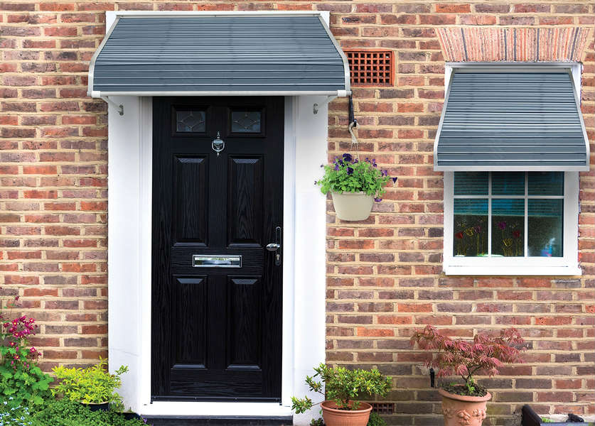 A black door and window on the side of a brick house.