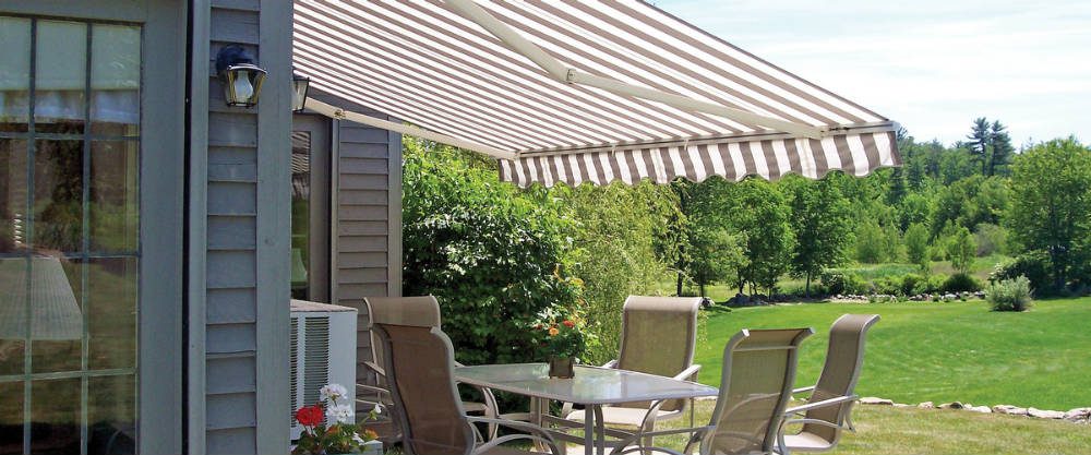 A patio with chairs and table under an awning.