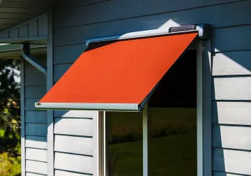 A red awning is attached to the side of a house.