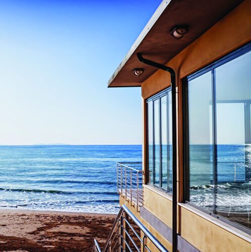 A building on the beach with water in the background.