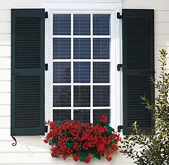 A window with shutters and flowers in the window.
