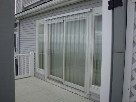 A sliding glass door with white curtains on the outside.