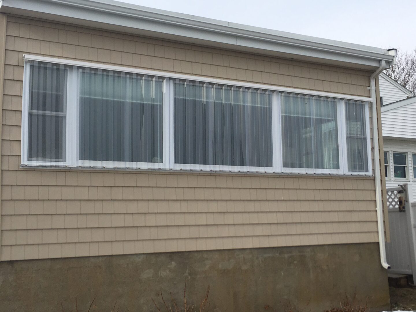 A house with three windows and a concrete wall.