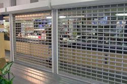 A store front with a glass door and a metal grill.